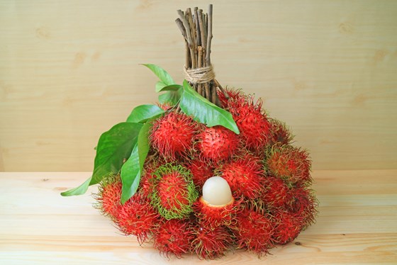A bunch of Rambutan fruits on a board surface
