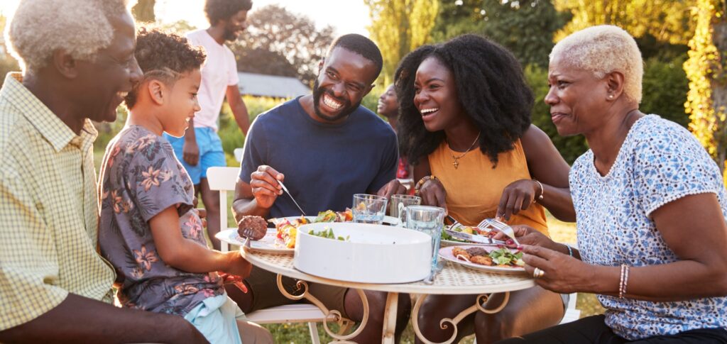 Family eating around a table in outdoors with smiling faces